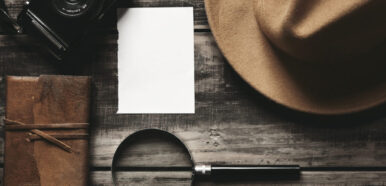 Photo camera, notebook, hat, magnifier, paper on black table Photo camera, notebook, hat, magnifier, paper on black table
